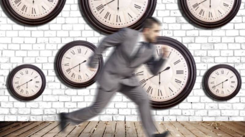 Blurry businessman running in front of multiple clocks
