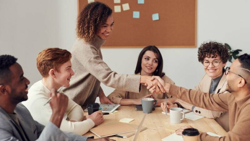 Collaborating financial services professionals shaking hands around table