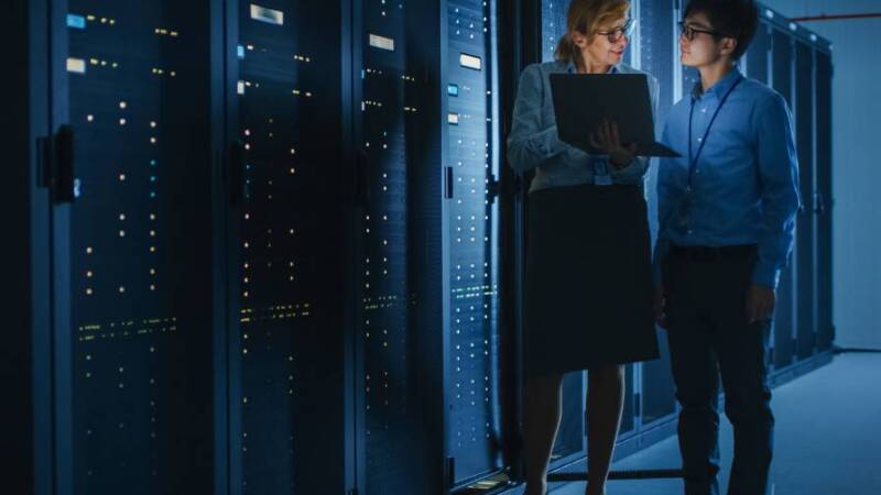 Two office workers on the computer standing outside of a server room